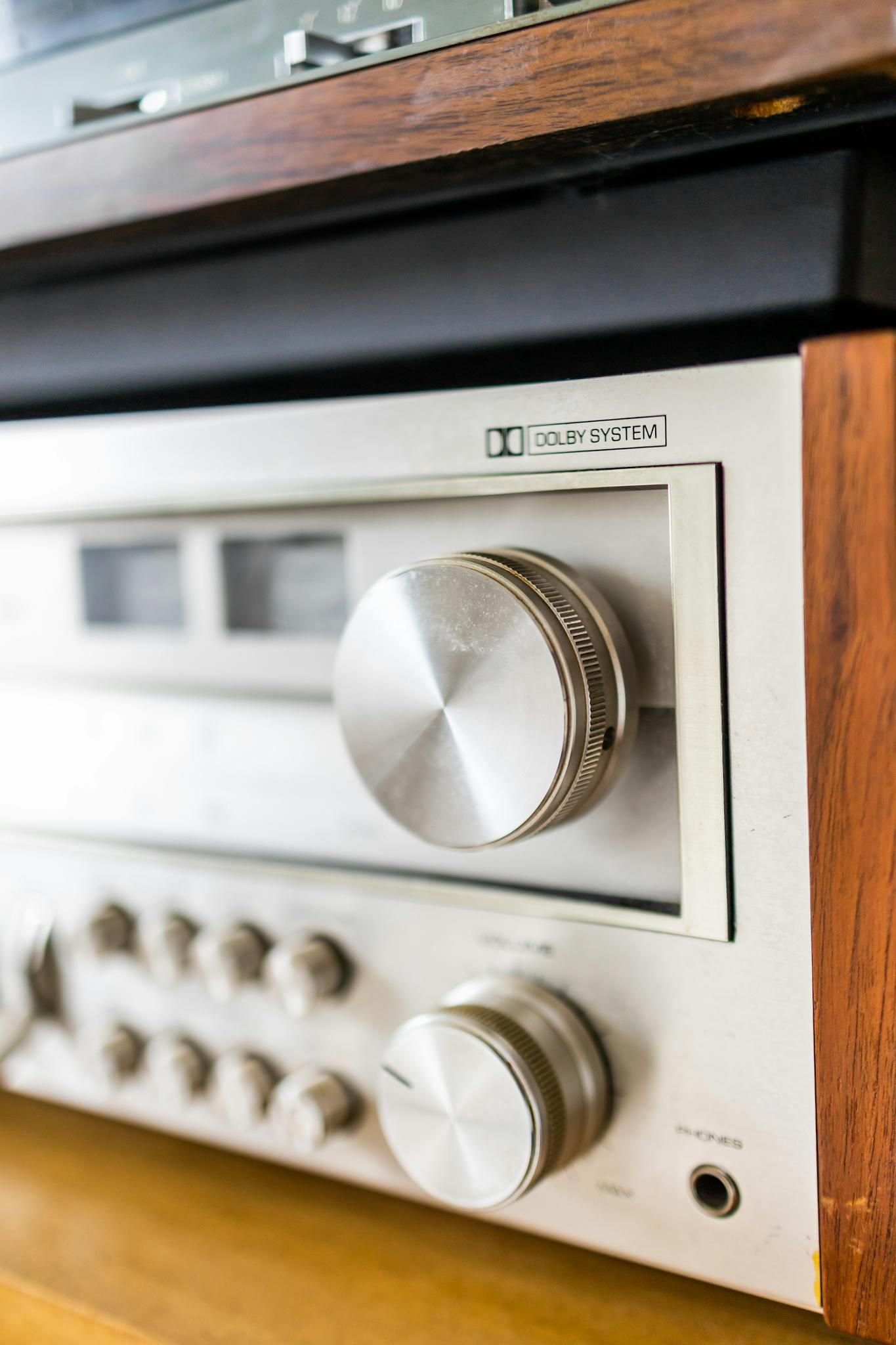 Close-up of a vintage silver stereo amplifier with focus on control knobs and wooden details.